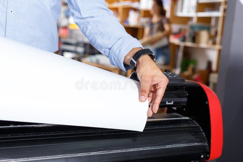 printer operator next to the printing machine holding printing
