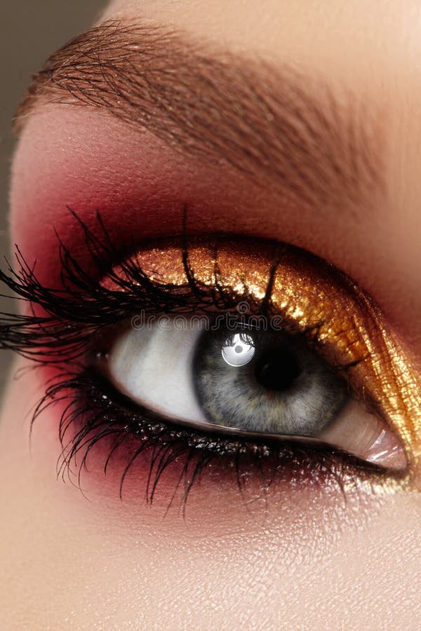 Close-up vrouwelijk oog met manier heldere samenstelling De mooie gouden, rode oogschaduw, schittert, zwarte eyeliner Vormwenkbra stock afbeeldingen Close-up vrouwelijk oog met manier heldere samenstelling De mooie gouden, rode oogschaduw, schittert, zwarte eyeliner Vormwenkbra stock afbeeldingen