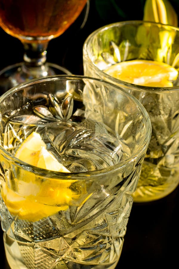 Close up of a wet glass of cold light beer with foam and vermouth Martini alcohol cocktail with yellow lemon slice and ice cubes o royalty free stock photography Close up of a wet glass of cold light beer with foam and vermouth Martini alcohol cocktail with yellow lemon slice and ice cubes o royalty free stock photography
