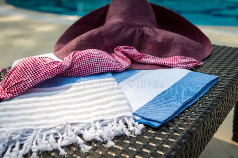 Close-up of white, blue and beige Turkish peshtemal / towel, pink bikini top and straw hat on rattan lounger. royalty free stock image Close-up of white, blue and beige Turkish peshtemal / towel, pink bikini top and straw hat on rattan lounger. royalty free stock image