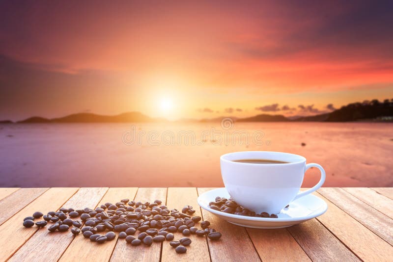 White coffee cup and coffee beans on wood table and view of suns