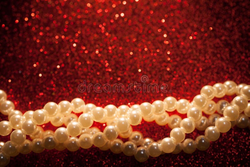 Close up of white pearls on a red glitter background.