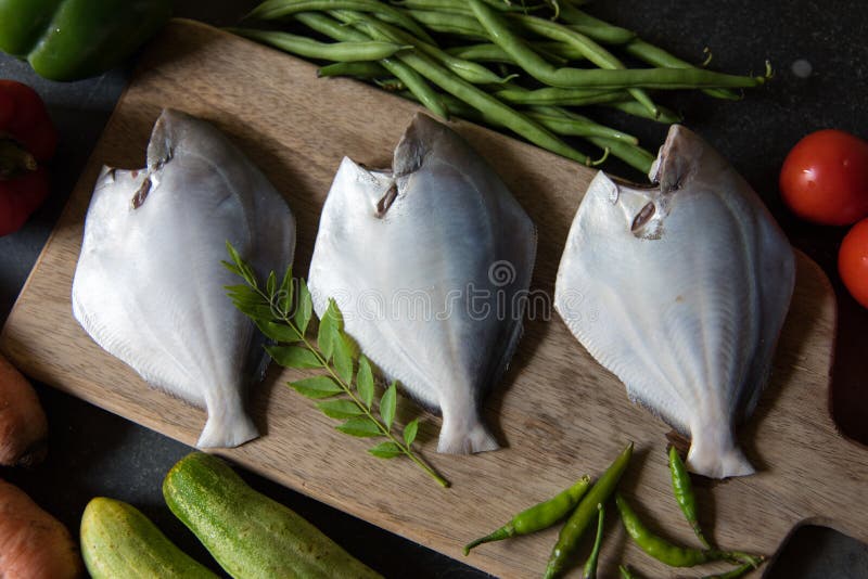 Close up of white pomfret fish on a wooden chopping board