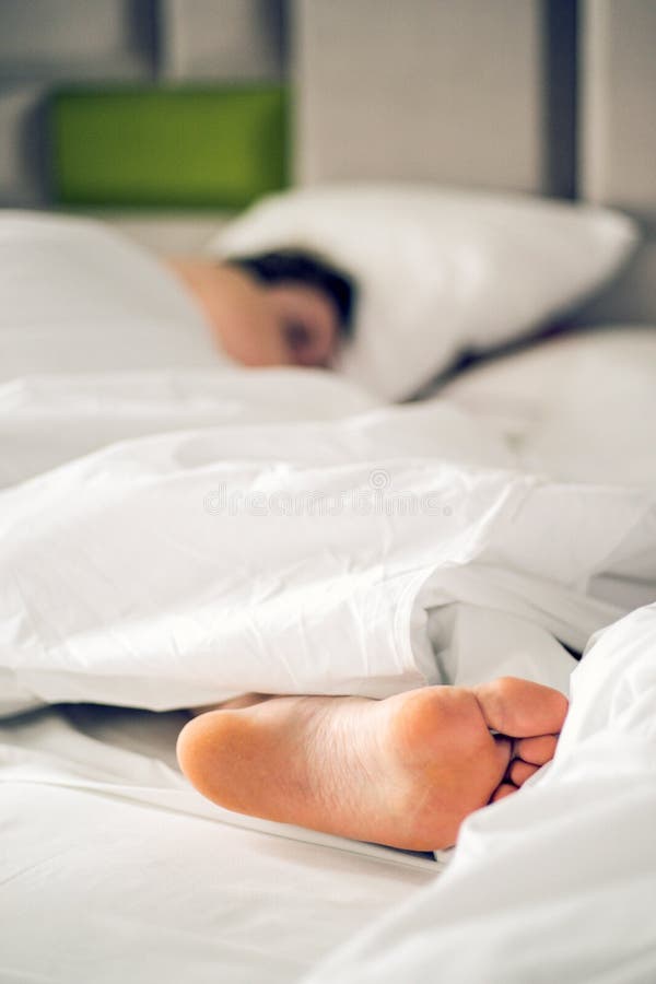 Close up woman bare feet on the bed over white blanket and bed sheet in the bedroom of home or hotel. Sleeping and relax concept. royalty free stock images Close up woman bare feet on the bed over white blanket and bed sheet in the bedroom of home or hotel. Sleeping and relax concept. royalty free stock images