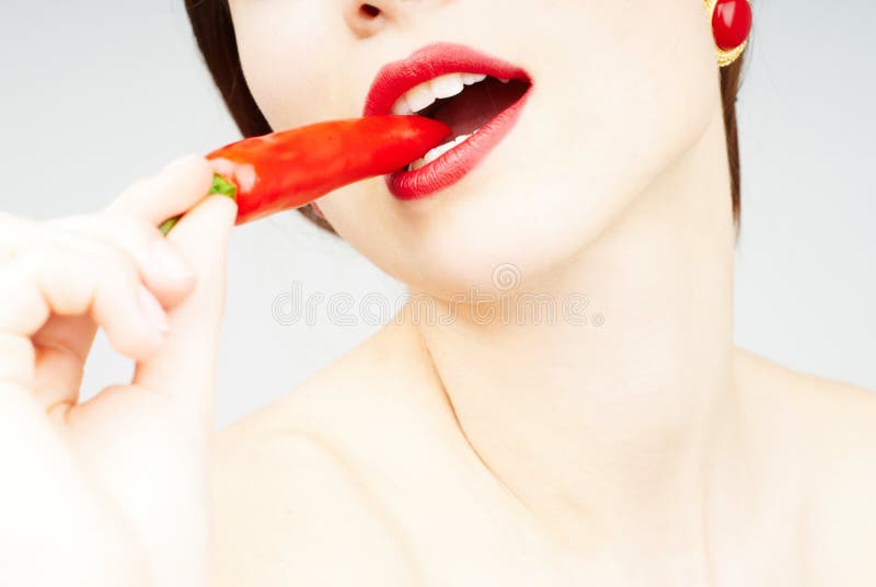 Close-up of a woman biting a chili pepper