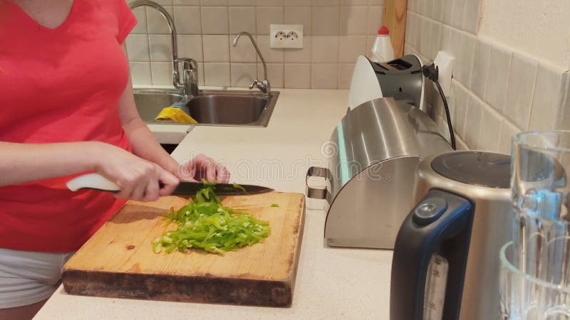 Close-up. woman cuts green paprika on wooden board at home kitchen royalty free stock photos Close-up. woman cuts green paprika on wooden board at home kitchen royalty free stock photos