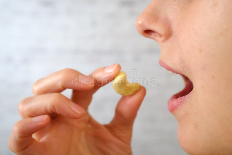 Close-up of woman eating cashew nuts stock images