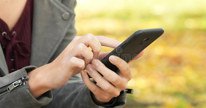 Woman hand using smart phone in a park