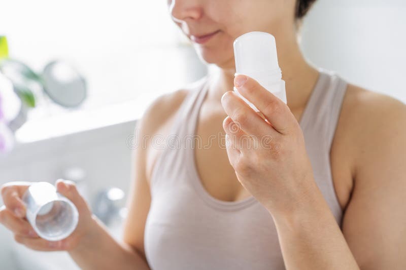 Close up woman holding natural crystal alum deodorant in modern bathroom. Eco friendly natural beauty and hygiene stock photo