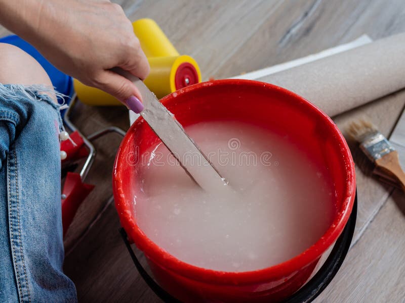 Wallpaper paste in bucket on the floor. Mixing wallpaper glue in bucket.  Apartment renovation concept Stock Photo - Alamy