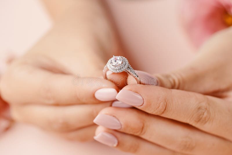 Close up of woman`s hand holding elegant diamond ring.