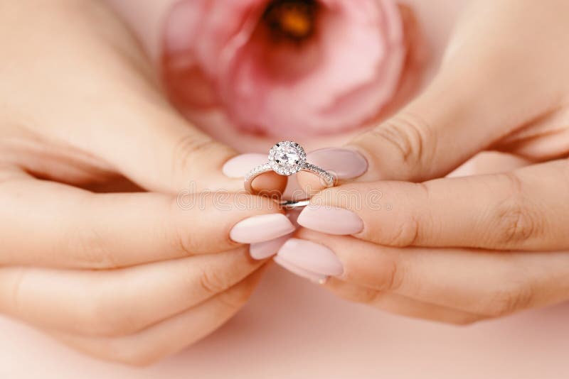 Close up of woman`s hand holding elegant diamond ring.