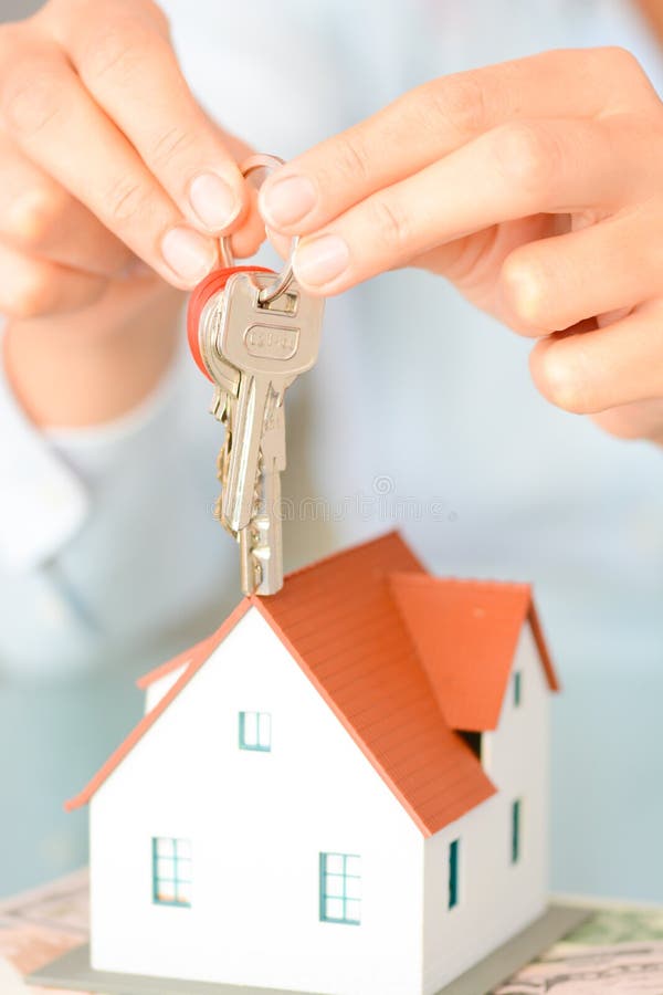 Close-up of woman`s hands holding a model house and a key suggesting house acquisition or rental stock photo Close-up of woman`s hands holding a model house and a key suggesting house acquisition or rental stock photo