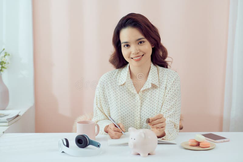 Close up of woman smiling putting a coin inside piggy bank as investment
