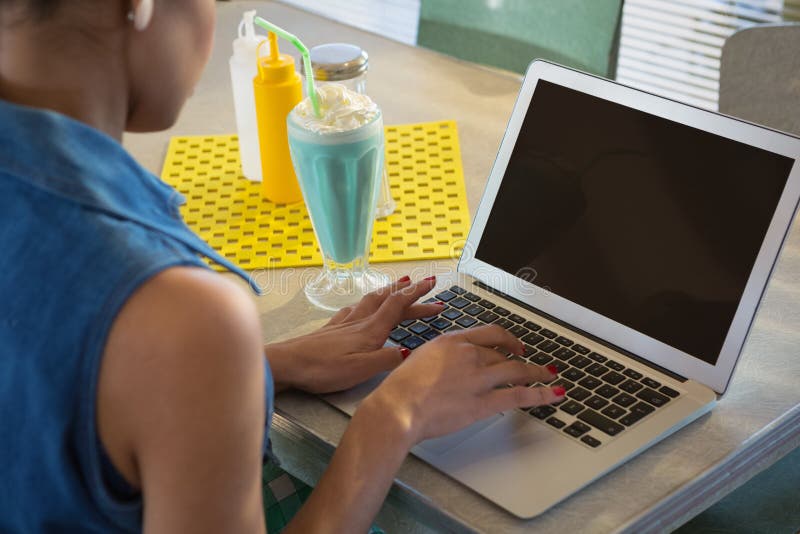 Woman using laptop while having milkshake in the restaurant royalty free stock photos Woman using laptop while having milkshake in the restaurant royalty free stock photos