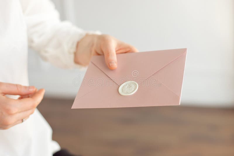 Close-up of woman in white shirt of business style holds in her hand a invitation card, card, letter. royalty free stock photography Close-up of woman in white shirt of business style holds in her hand a invitation card, card, letter. royalty free stock photography