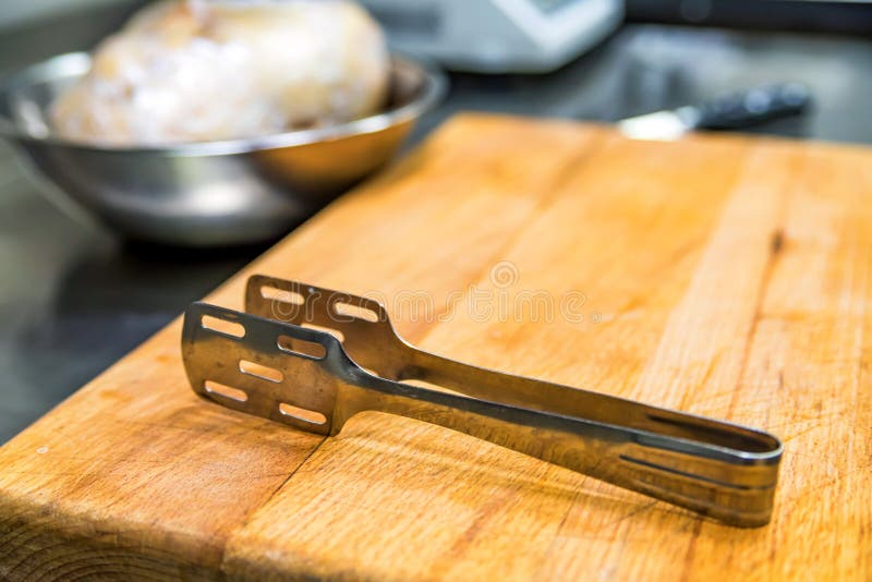 Metal Kitchen Thongs on Wooden Board Stock Image - Image of board, cheddar:  109759161