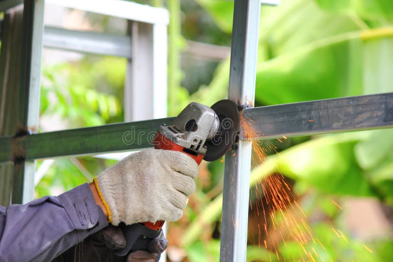 Close Up Worker Using Angle Grinder Polishing Steel Structure with Yellow Sparks Stock Photo