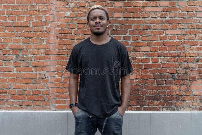 Young attractive dark-skinned man in black T-shirt on red bricked background. stock images
