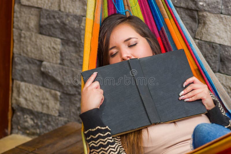 Close up of young beautiful woman sleeping in a hammock and holding a book with her hands, in blurred background royalty free stock image Close up of young beautiful woman sleeping in a hammock and holding a book with her hands, in blurred background royalty free stock image