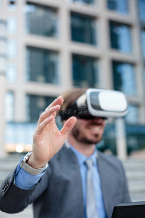 Close up of a young businessman using VR goggles in front of an office building, making hand gestures. Selective focus on his hand royalty free stock images Close up of a young businessman using VR goggles in front of an office building, making hand gestures. Selective focus on his hand royalty free stock images