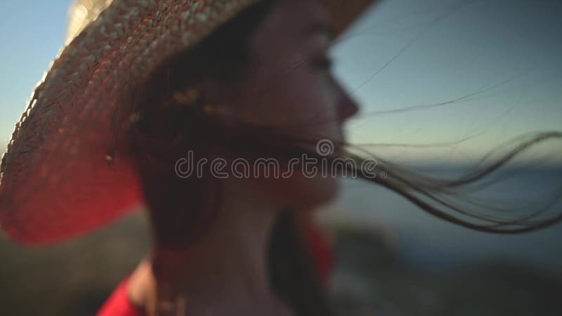 Close-up of a young Caucasian woman&x27;s hair fluttering in slow motion in the wind. Shallow depth of field. Girl in red