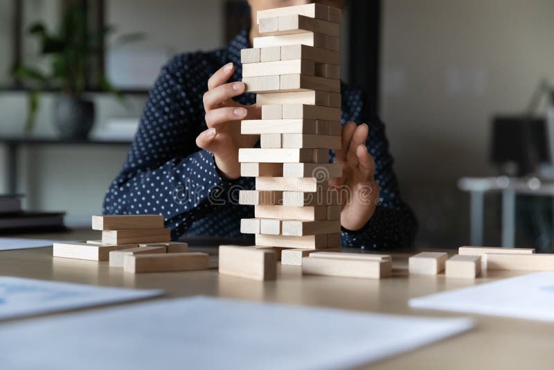 Close up young indian woman constructing tower with wooden bricks.