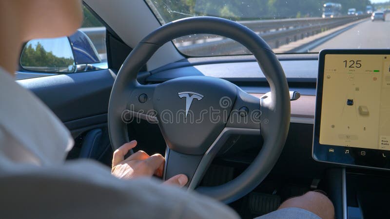 CLOSE UP: Young man commuting to work drives down an empty highway in a Tesla. stock image