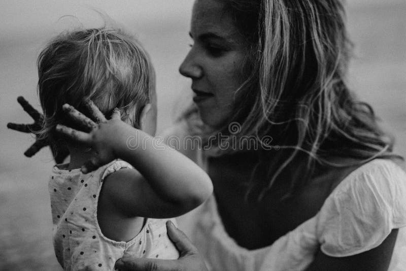 Close-up of young mother with a toddler girl on beach on summer holiday. royalty free stock photography Close-up of young mother with a toddler girl on beach on summer holiday. royalty free stock photography