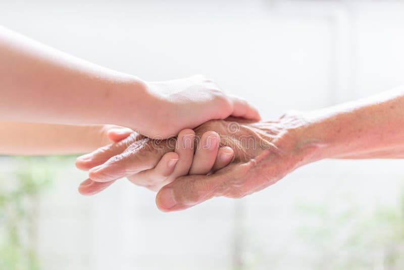 Close up of young woman hand holding with tenderness an elderly senior person hands,people,age,family,care and support concept