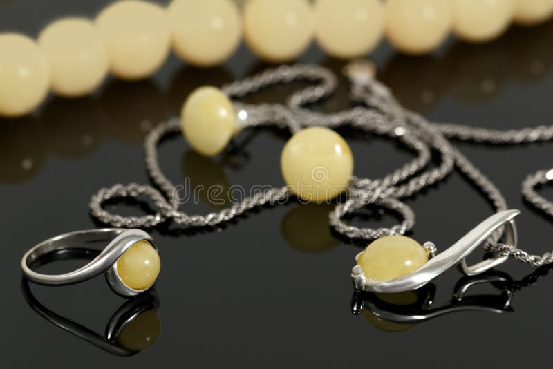 Close-up zilveren tegenhanger en ring met amber op achtergrond van oorringen en parels op zwarte raad stock fotografie Close-up zilveren tegenhanger en ring met amber op achtergrond van oorringen en parels op zwarte raad stock fotografie