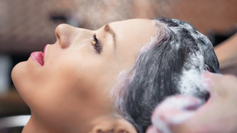 Close-upgezicht van aanbiddelijke vrouw met perfecte huid die was van haar met shampoo genieten door kapper