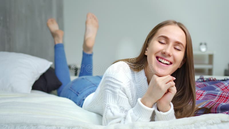 Close-upgezicht van gelukkig meisje die pret hebben die op bed in en slaapkamer liggen die genieten van ontspannen