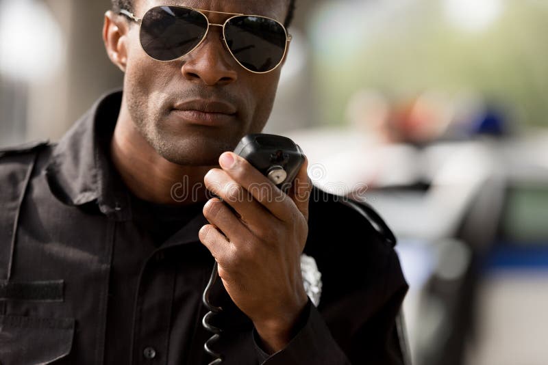close-upportret van Afrikaanse Amerikaanse politieman die door walkie-talkie spreken
