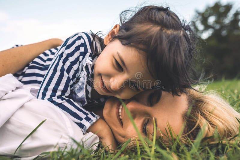 Close-upportret van het jonge Kaukasische vrouw liggen op het groene gras en het omhelzen van haar weinig dochter in het park Hou royalty-vrije stock afbeeldingen Close-upportret van het jonge Kaukasische vrouw liggen op het groene gras en het omhelzen van haar weinig dochter in het park Hou royalty-vrije stock afbeeldingen