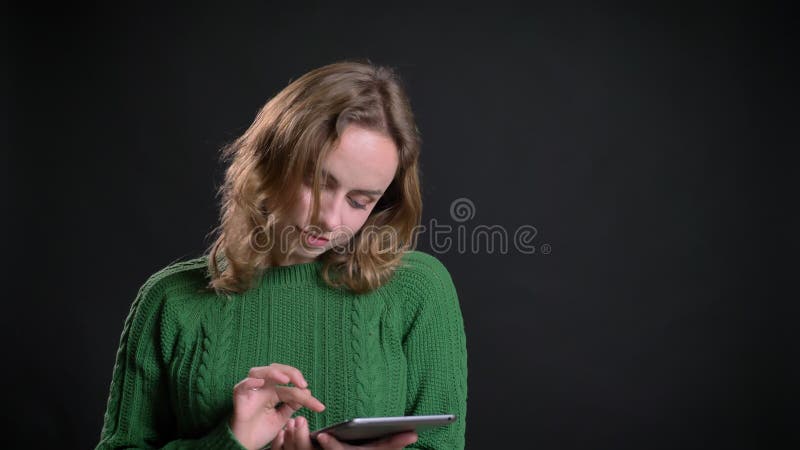 Close-upportret van het volwassen Kaukasische vrouw doorbladeren op de tablet voor de camera