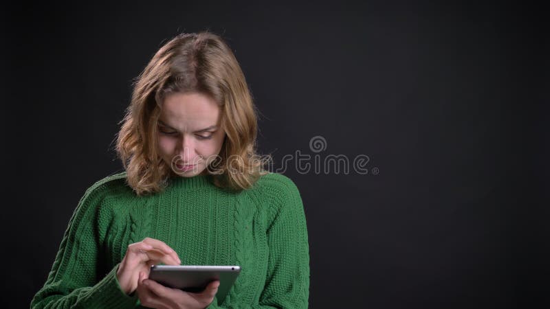 Close-upportret van het volwassen Kaukasische vrouwelijke scrollen op de tablet die bij camera kijken en het glimlachen