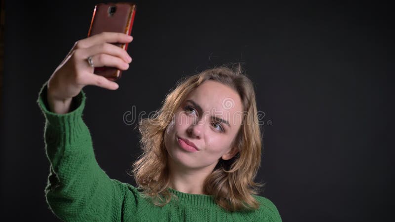 Close-upportret van volwassen Kaukasisch wijfje die selfies op de telefoon nemen en haar haar bevestigen