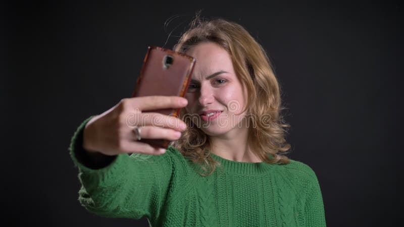 Close-upportret van volwassen Kaukasisch wijfje die selfies op de telefoon nemen en verschillende gelaatsuitdrukkingen maken