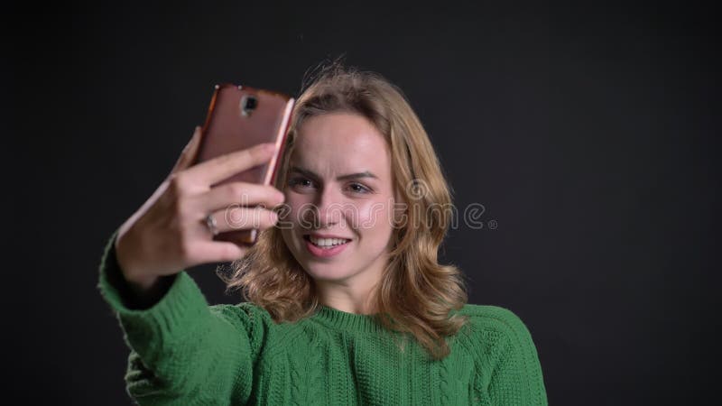 Close-upportret van volwassen Kaukasische vrouw die een videogesprek op de telefoon hebben die en met haar hand glimlachen golven