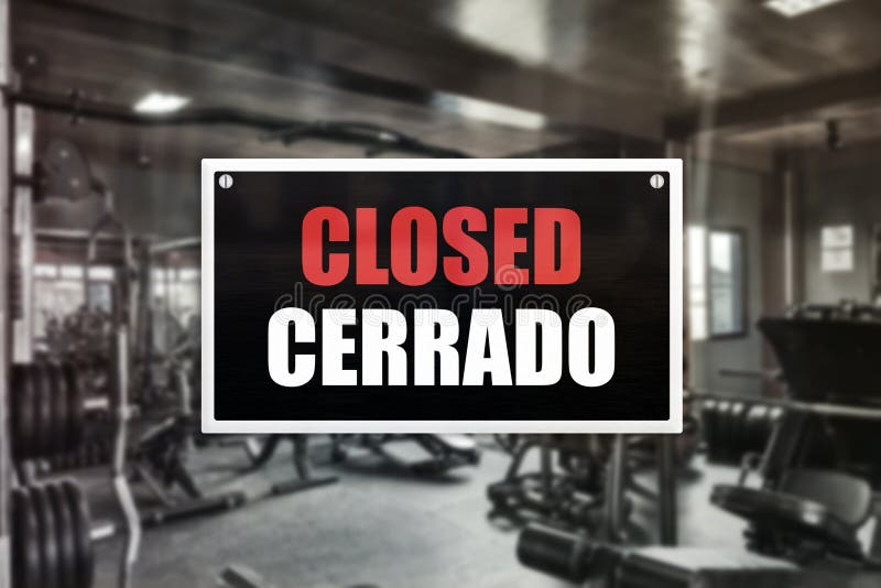 A Closed Sign with Spanish Translation in Front of a Gym Stock Image