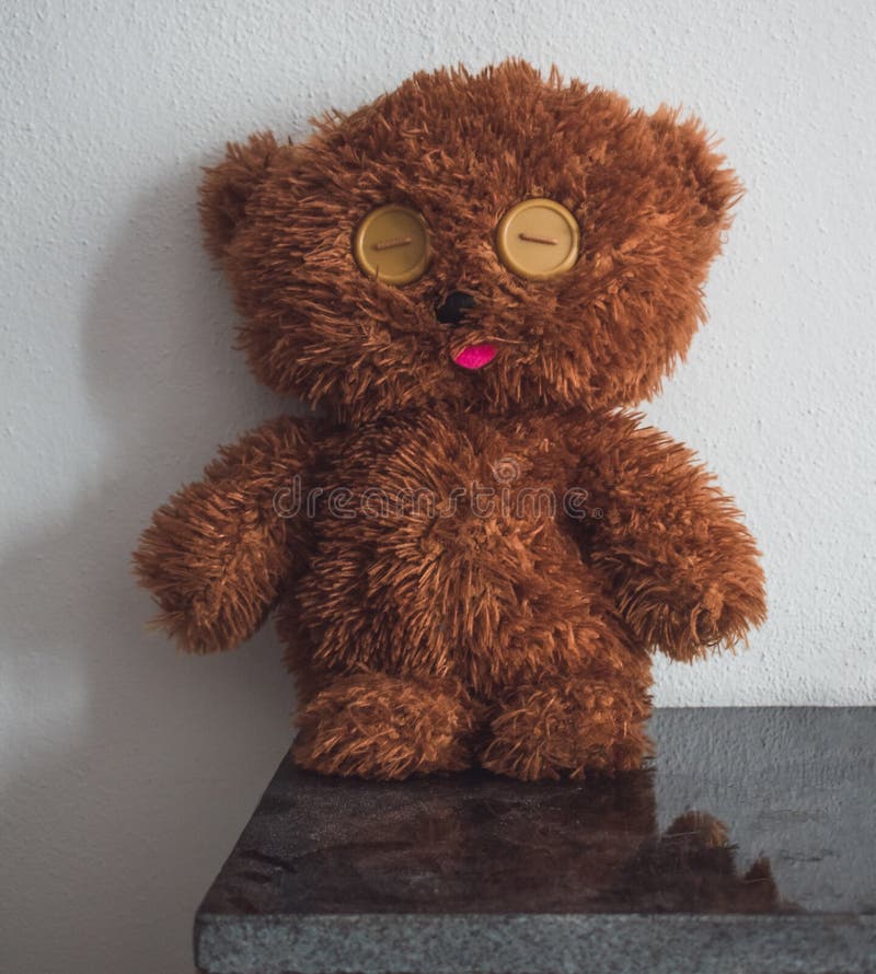 Closeup of an adorable brown teddy bear leaned on the wall stock photo
