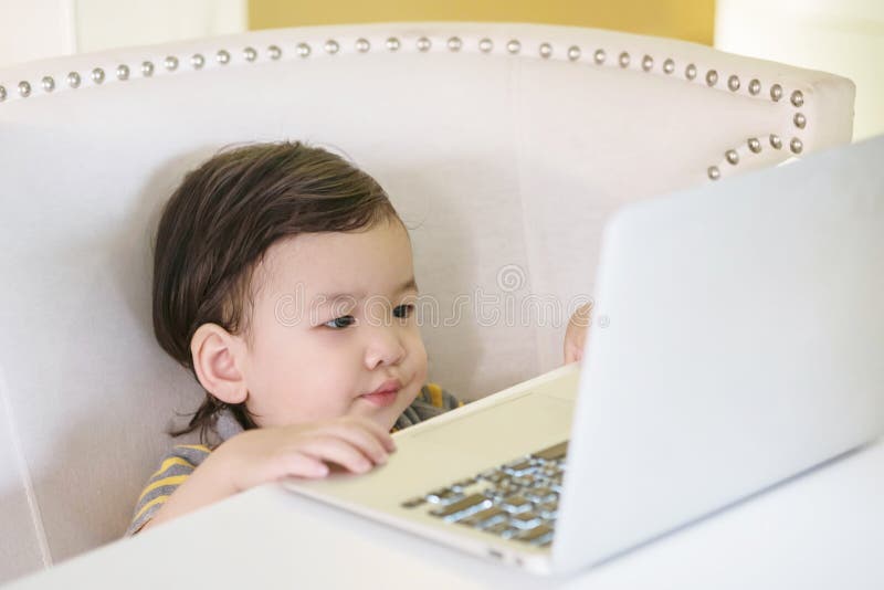 Closeup asian kid use computer notebook for watch cartoon in the house background