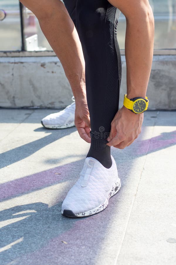 Closeup of an Athlete Man Adjusting His Socks Outdoors Stock Photo