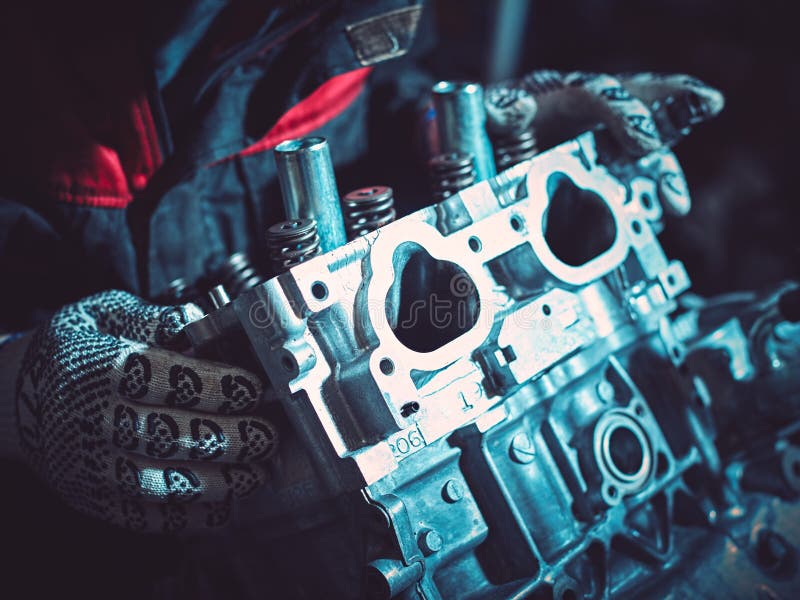 Closeup of an auto mechanic working on a car engine. Closeup of an auto mechanic working on an automobile engine. Installing the intake manifold on the opposing engine.