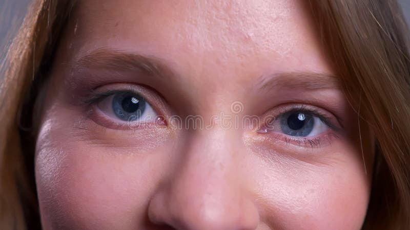 Closeup av charmiga unga caucasian kvinnliga blåa ögon som ser raka på kameran med lyckligt ansiktsuttryck lager videofilmer Closeup av charmiga unga caucasian kvinnliga blåa ögon som ser raka på kameran med lyckligt ansiktsuttryck lager videofilmer