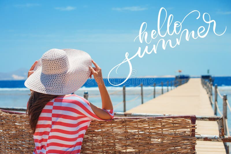 Closeup back view of woman in white hat looking out towards blue ocean and sky and words Hello summer. Calligraphy stock photos Closeup back view of woman in white hat looking out towards blue ocean and sky and words Hello summer. Calligraphy stock photos