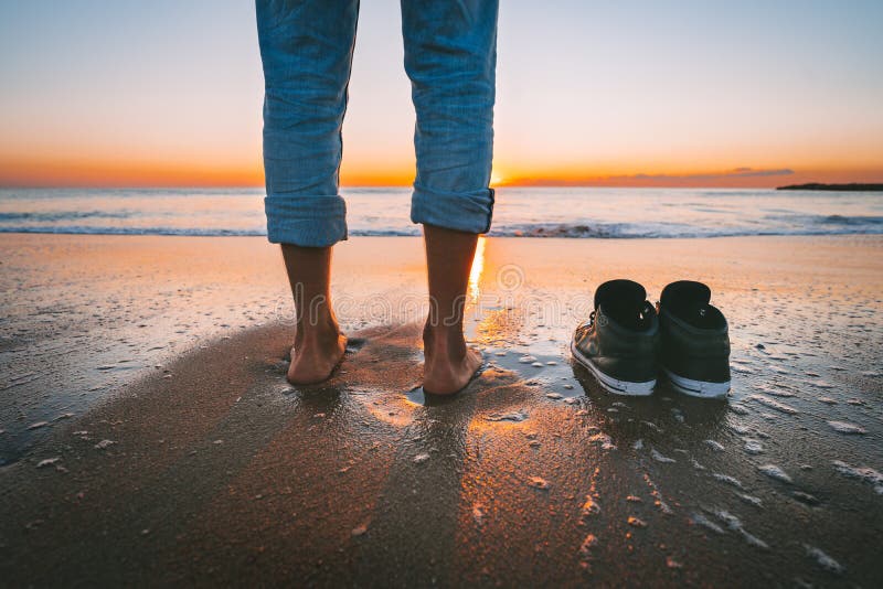 Closeup of barefoot man walking on the summer beach at sunset. Without shoes