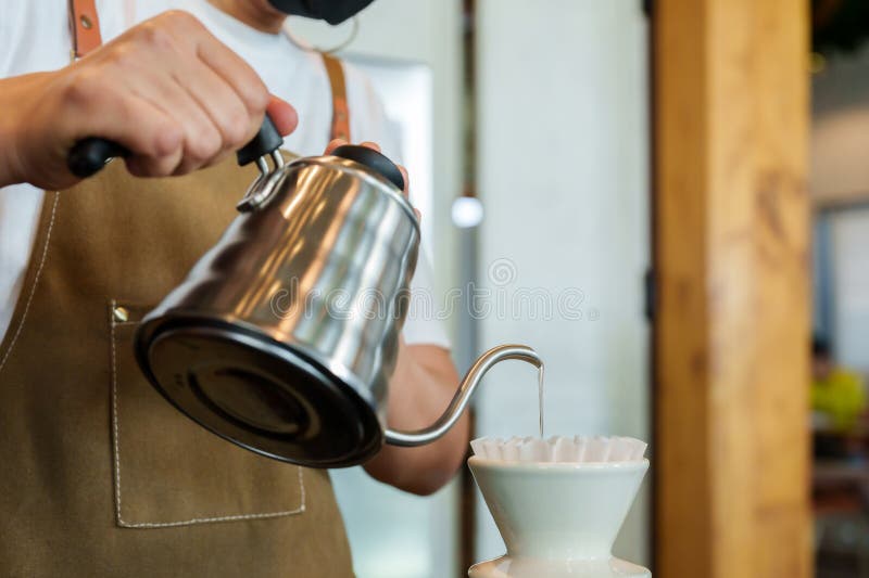 Closeup barista care ține ceainicul și care toarnă pudră de cafea în dispozitivul pentru a bea cafea, în timp ce prepară barista stock image