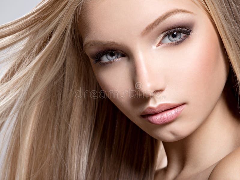 Closeup Beautiful  face of young woman with long white hair - posing at studio over gray background